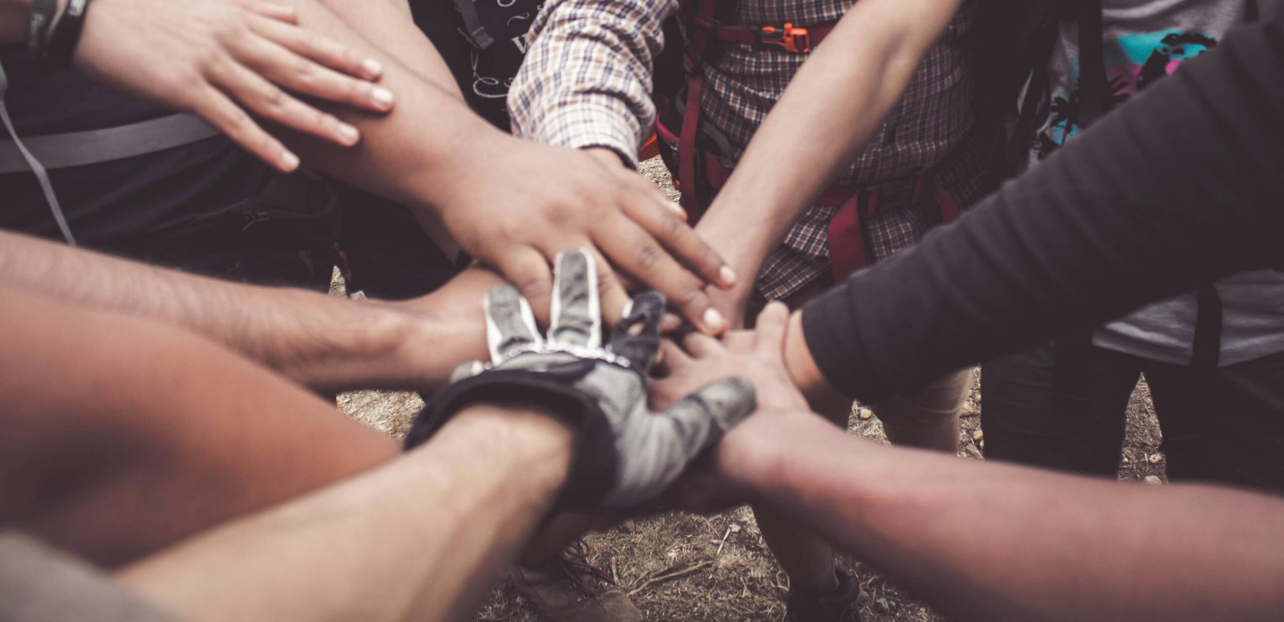 A group of diverse individuals join hands for teamwork in West Java, Indonesia.